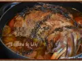 Épaule d'agneau rôtie dans un plat avec des herbes et des légumes.