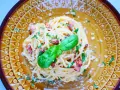Pyszna carbonara ze szparagami, udekorowana bazylią i posypana parmezanem, na ozdobnym talerzu.