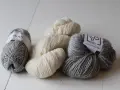 Mjuka garnnystan i grått och naturvitt. Perfekt ullgarn som inte kliar, redo att bli ditt nästa stickprojekt.