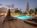 Basen hotelowy oświetlony nocą, leżaki i palmy. Idealne miejsce na relaks, zgodnie z licznymi heronissos hotel opinie.
