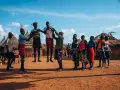 Ludzie w tradycyjnych strojach tańczą przed chatami. Czy Uganda jest bezpiecznie? Tak, w takich miejscach można poczuć się bezpiecznie.