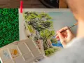 Une main peint un paysage marin, une excellente idée peinture facile pour capturer la beauté de la nature.