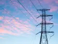 Wieża z przewodami linii energetycznej średniego napięcia na tle różowo-niebieskiego nieba.