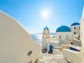 Santorini, październik. Słoneczna pogoda, białe domy i niebieskie kopuły kościołów nad Morzem Egejskim.