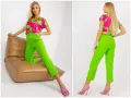 Modelka prezentuje stylizację: jaka bluzka do zielonych spodni? Neonowe spodnie i fuksjowa bluzka z zielonym wzorem.