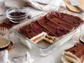 En krämig tiramisu i glasform, perfekt för ett enkelt tiramisu recept. Toppad med kakao, kaffebönor och lila blommor.