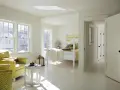 Luminosa camera da letto con **colore pareti bianco caldo**, due poltrone gialle, letto a baldacchino e luce solare che filtra dalle finestre.