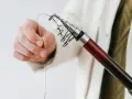 Dłoń trzyma żyłkę przy szczytówce wędki spinningowej.