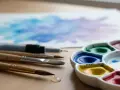 Un pinceau et une palette d'aquarelle colorée, prêts à créer une œuvre d'art sur une feuille blanche.
