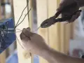 Ręce przycinają przewody do skrzynki elektrycznej. To kluczowy krok, by dowiedzieć się, jak zostać elektrykiem.