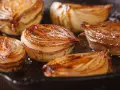 Moitiés d'oignons caramélisés, dorés et juteux, cuisant dans une poêle.