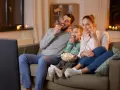 Rodzina zajada popcorn podczas oglądania filmów familijnych.