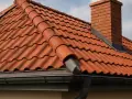 Czerwona dachówka tworzy solidne opierzenie dachu, chroniąc dom przed deszczem. Kominek z cegły dodaje uroku.