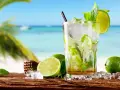 Orzeźwiające drinki z miętą i limonką na tle plaży. Idealne na upalne dni.