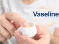 Eine Hand entnimmt Vaseline aus einem Tiegel. Das Produkt besteht aus Petrolatum, einem Gemisch aus Kohlenwasserstoffen.