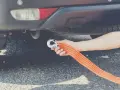 Dłoń mocuje hak liny holowniczej do haka holowniczego auta. To pokazuje, czy można holować auto na linie.