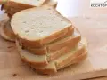 Gestapelte Scheiben eines hellen Sandwichbrots auf einem Holzbrett. Perfekt für ein einfaches Sandwich brot rezept.