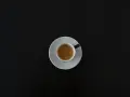 Czarna filiżanka espresso na białym spodeczku na ciemnym tle. Może symbolizować początek walki z objawami odstawienia kofeiny.