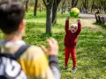 Un enfant joyeux lance un ballon en l'air dans un parc, un autre enfant est devant.
