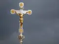 Ein goldenes Kruzifix mit Jesus vor dramatischem Himmel. Die Frage, wie lange dauert die Osterzeit, hallt nach.