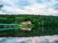 Malowniczy hotel nad jeziorem, z mostem i lasem w tle. Idealne miejsce na wypoczynek i odkrywanie tleń atrakcji.