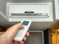 Mano ajustando el control remoto del aire acondicionado a 20 grados, ideal para saber a cuanto poner el aire acondicionado en verano y refrescar el hogar.