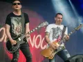 Dwóch gitarzystów na scenie, jeden w czarnej koszulce z sercem, drugi w białej z żebrami. Kocham cię jak Irlandię, grają rocka.