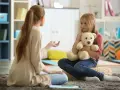 Przykładowa rozmowa z psychologiem. Dziewczynka z misiem słucha uważnie terapeuty.