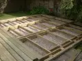 Drewniana konstrukcja tarasu w trakcie budowy. Podłoże podsypane żwirem, tworzące solidną podstawę dla przyszłej podłogi.