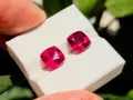 Due gemme rosse intense, la pietra di luglio per eccellenza, brillano su un supporto bianco.