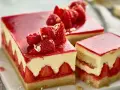 Deliziosa torta di fragole con strati di crema, fragole fresche e gelatina rossa, guarnita con frutti di bosco e foglia d'oro.
