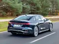 Ciemny Audi A4 B10 pędzi po drodze, otoczony jesiennym lasem.