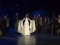 Scena z musicalu "Człowiek z La Manchy". W centrum młoda kobieta w białej sukni, otoczona przez grupę postaci w strojach z epoki.