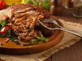 Saftiges Pulled Pork, perfekt zubereitet mit einem aromatischen pulled pork rub, liegt auf einem Holzbrett. Gabeln deuten auf den Genuss hin.