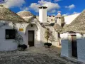 Urokliwe domki trulli z kamiennymi dachami, malownicze uliczki i błękitne niebo.