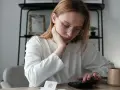 Zmartwiona kobieta z okularami liczy na kalkulatorze, szukając informacji, jak sprawdzić zadłużenie alimentacyjne.