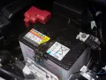 Autobatterie im Motorraum, mit Warnhinweisen. Die Batterie ist tiefentladen und muss ersetzt werden.