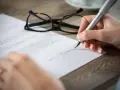 Eine Hand unterschreibt mit einem Füllfederhalter einen **Praktikumsvertrag**. Eine Brille liegt daneben.