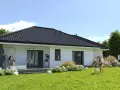 Rodzina cieszy się ogrodem przy nowoczesnym domu. Zastanawiasz się, ile kosztuje wybudowanie domu 120m2?