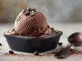 Ein Löffel Simons Eis, schokoladig und cremig, wartet neben Kakaopulver und Schokostückchen auf den Genuss.