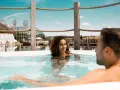 Ein Paar genießt die Entspannung im warmen Wasser am Badesee Sinsheim. Im Hintergrund ist die futuristische Architektur des Erlebnisbads zu sehen.