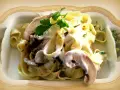 Pyszne tagliatelle z grzybami w kremowym sosie, udekorowane natką pietruszki.