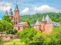 Magnifique ensemble de bâtiments en pierre rouge, dont une église romane et des tours, au milieu d'une végétation luxuriante. Idéal pour découvrir que faire autour de Rocamadour.