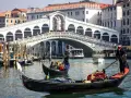 La gondola veneziana scivola sull'acqua, con il Ponte di Rialto sullo sfondo, un'icona di Venezia.