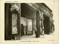 Façade de galerie de boutiques, style art déco, avec ornements floraux et motifs circulaires. Un homme en costume se tient sur le trottoir.