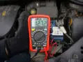 Multimetr pokazuje 12.72V, co może oznaczać, że akumulator nie trzyma napięcia. Sprawdzanie stanu baterii w samochodzie.