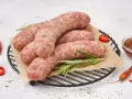 Surowa biała kiełbasa na ruszcie z rozmarynem, papryczkami chili i sosem. Dowiedz się, ile gotować białą kiełbasę, by była idealna.