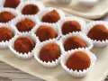 Deliciosas trufas de chocolate cubiertas de cacao, presentadas en sus envoltorios blancos.