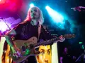 John 5 mit seinem charakteristischen Make-up spielt Gitarre, im Hintergrund ein Bild von Marilyn Manson.