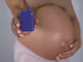 Mujer embarazada sostiene un vapeador morado, sugiriendo la opción de vapear embarazo sin nicotina.